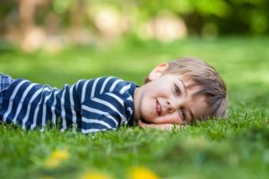 Smiling little boy lying on the grass in the park